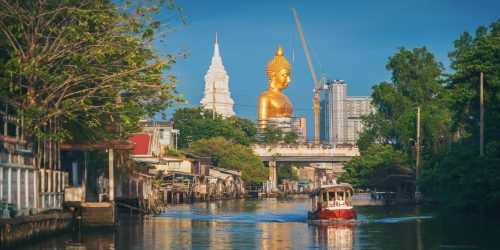 The Giant Golden Buddha in Wat Paknam Phasi Charoen Temple in Phasi Charoen district with boat on Chao Phraya River, Bangkok urban city, Thailand.